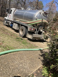 a truck with a hose parked next to bushes