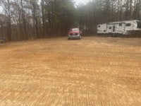 a rv parked on a dirt lot in the woods