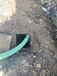 a green hose is attached to a hole in the ground